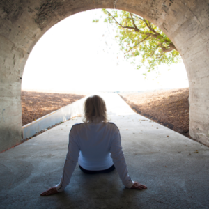 woman sitting looking out from a tunnel